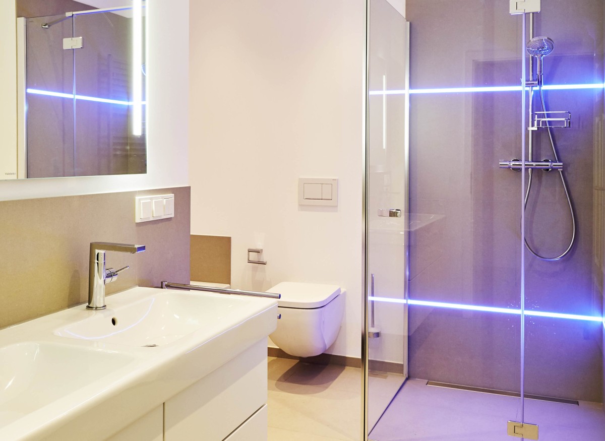 Modernes Badezimmer Das neue Badezimmer wurde mit Doppelwaschtisch, WC, Dusche, Badewanne und großformatigen Fliesen ausgestattet. In die Wandfliesen wurde LED-Beleuchtung integriert.