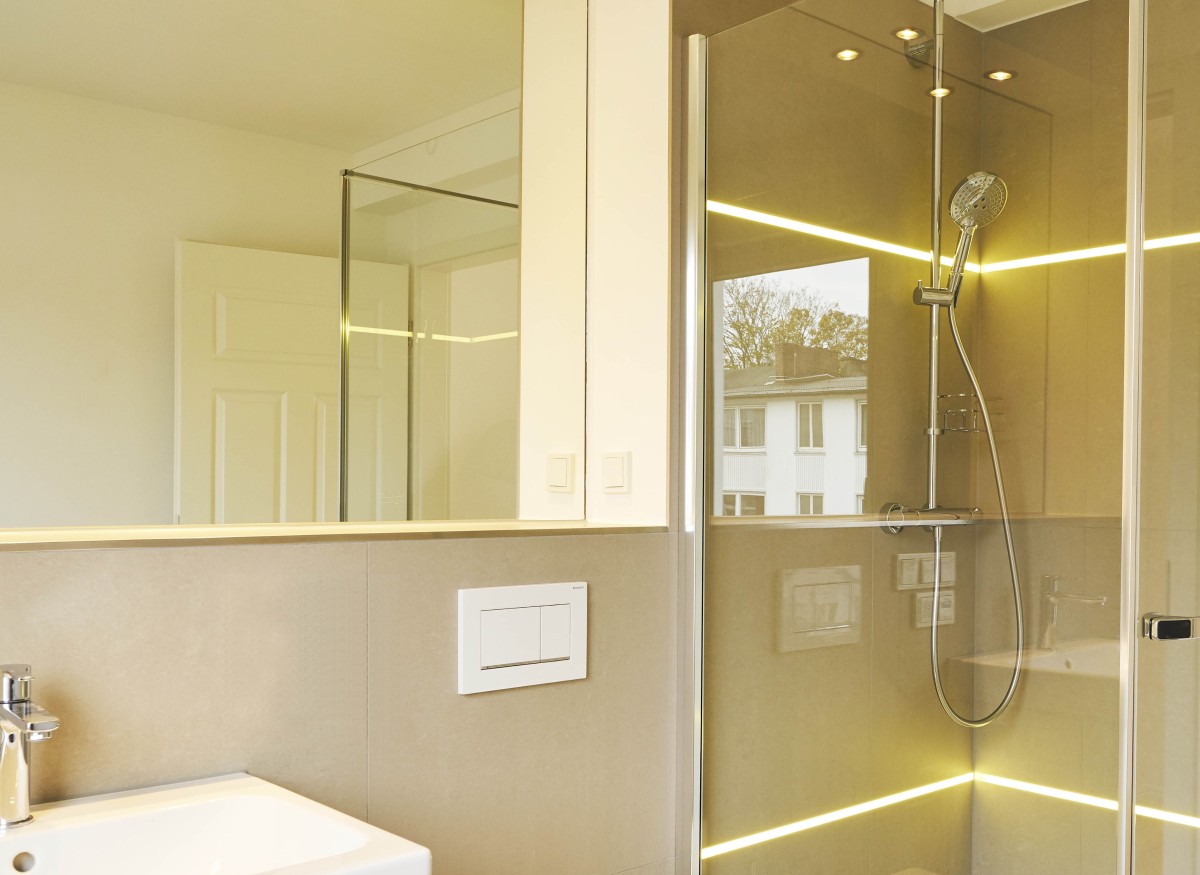 Modernes Badezimmer Das neue Badezimmer wurde mit Doppelwaschtisch, WC, Dusche und großformatigen Fliesen ausgestattet. In die Wandfliesen wurde LED-Beleuchtung integriert.